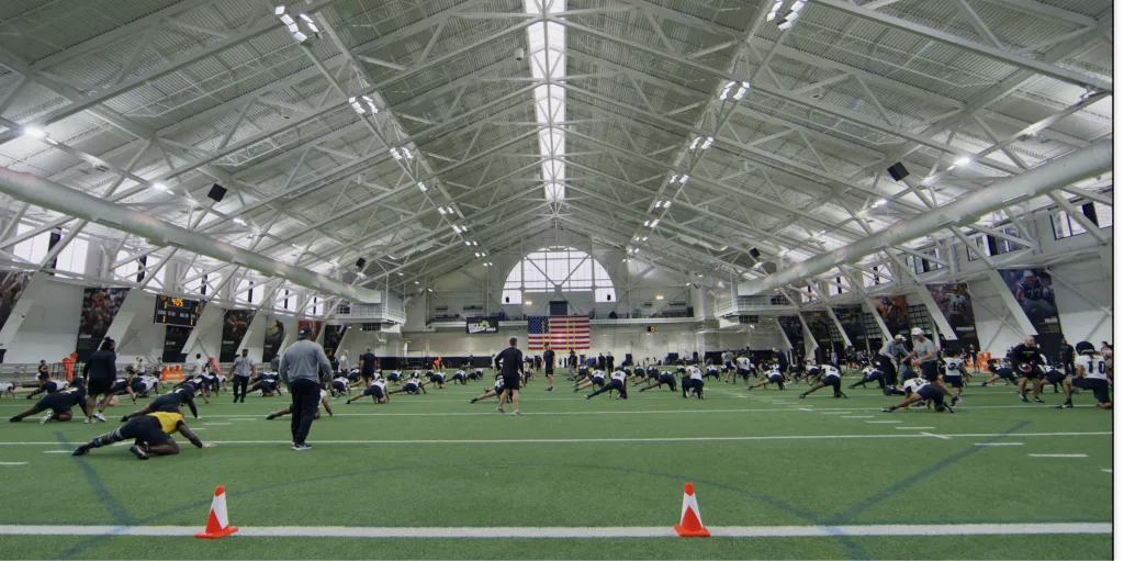 Team stretching on the turf of an indoor practice facility