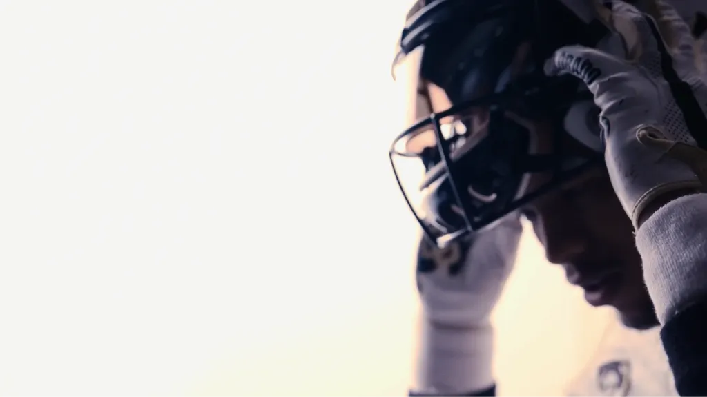 Football player in helmet and gloves, close up
