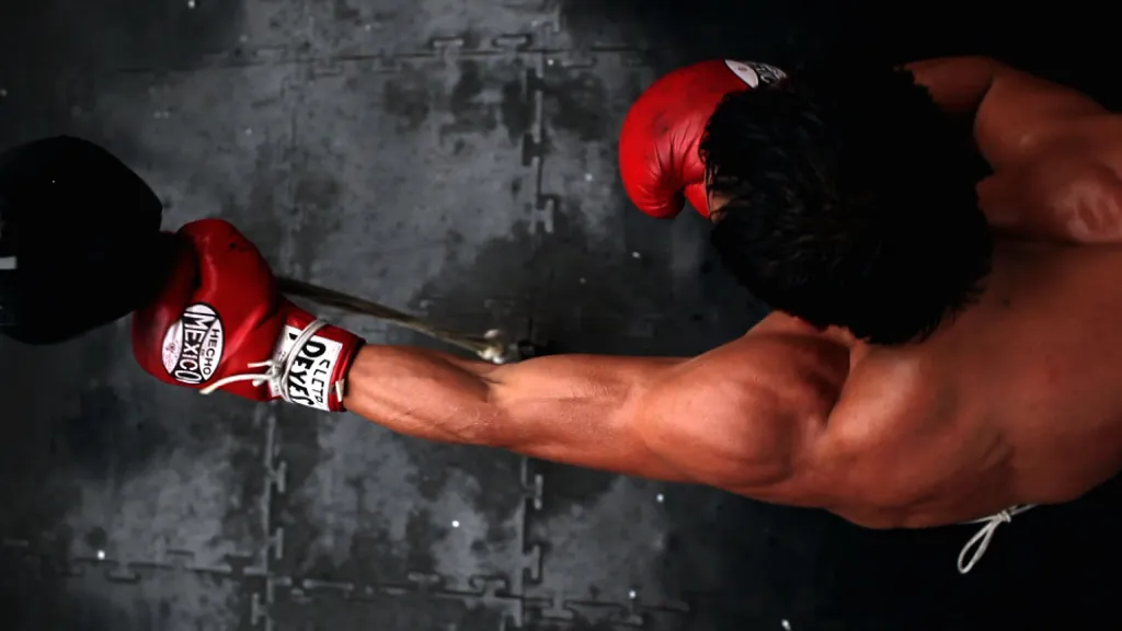Overhead view of a boxer in red gloves striking a heavy bag